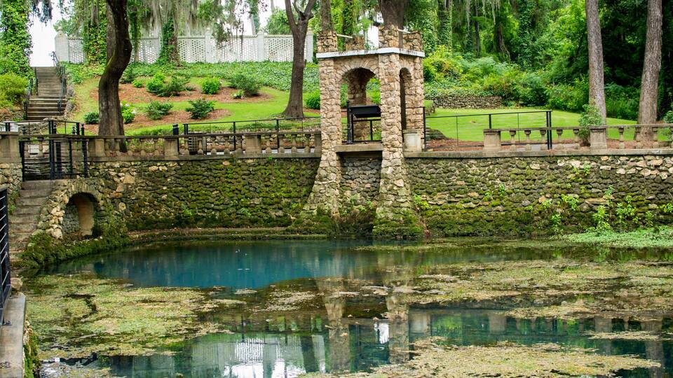 A stone bridge over a pond with moss-covered walls and a stone archway.