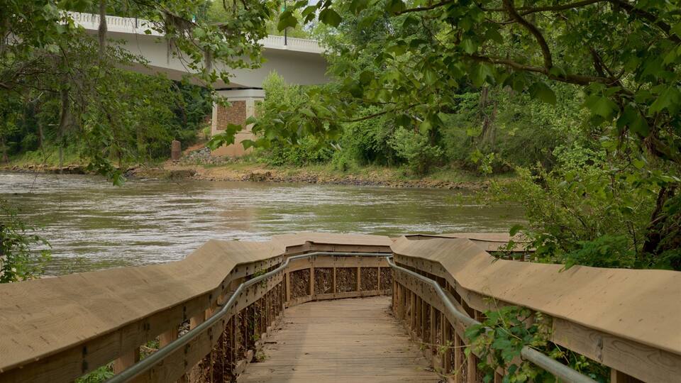 A wooden bridge over a river with greenery on both sides.