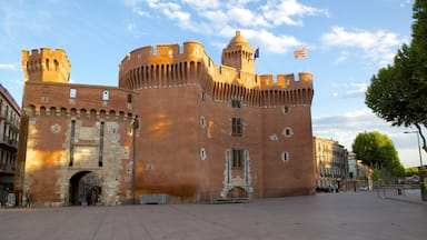 Un castillo de ladrillo histórico con múltiples torres y una cúpula central, con un asta de señales y dos banderas.
