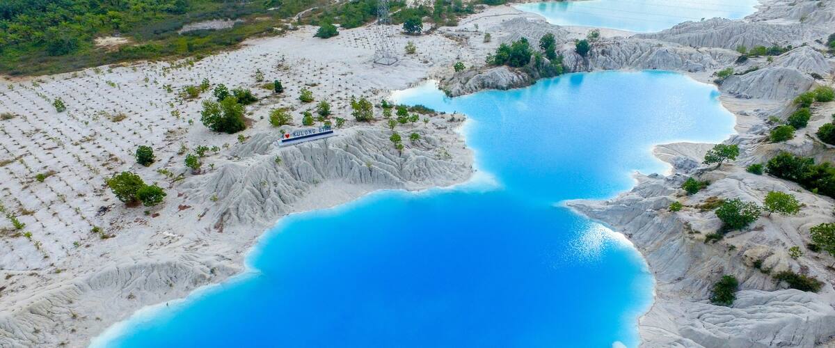 A large, clear blue lake surrounded by rocky terrain with sparse vegetation.