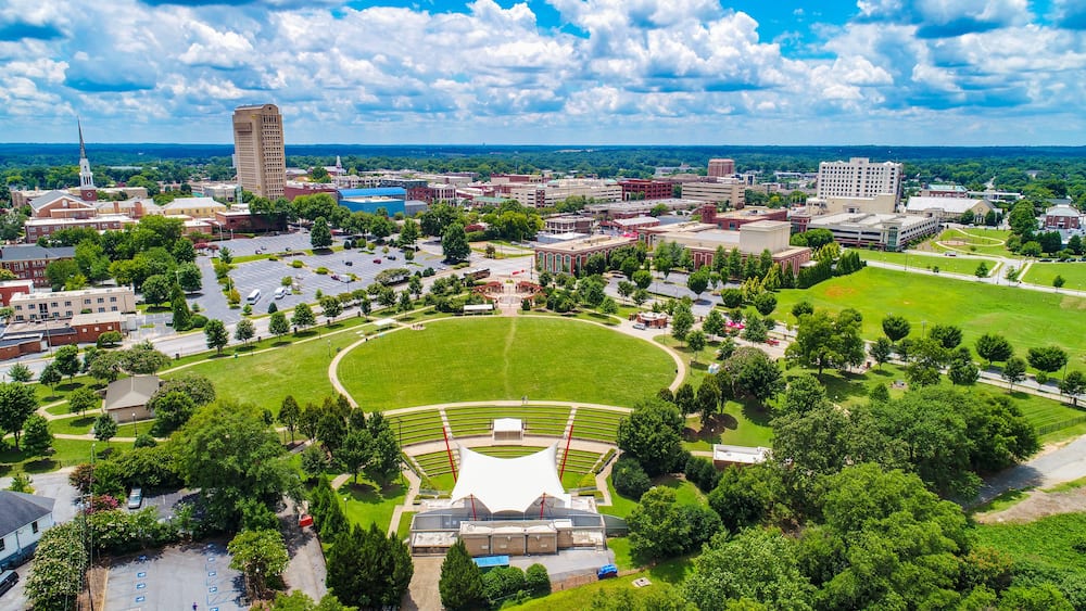 A university campus with a large green field, a stadium, and surrounding buildings.