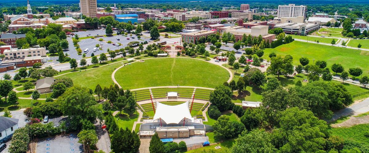 Un campus universitario con un amplio campo verde, un estadio y edificios circundantes.