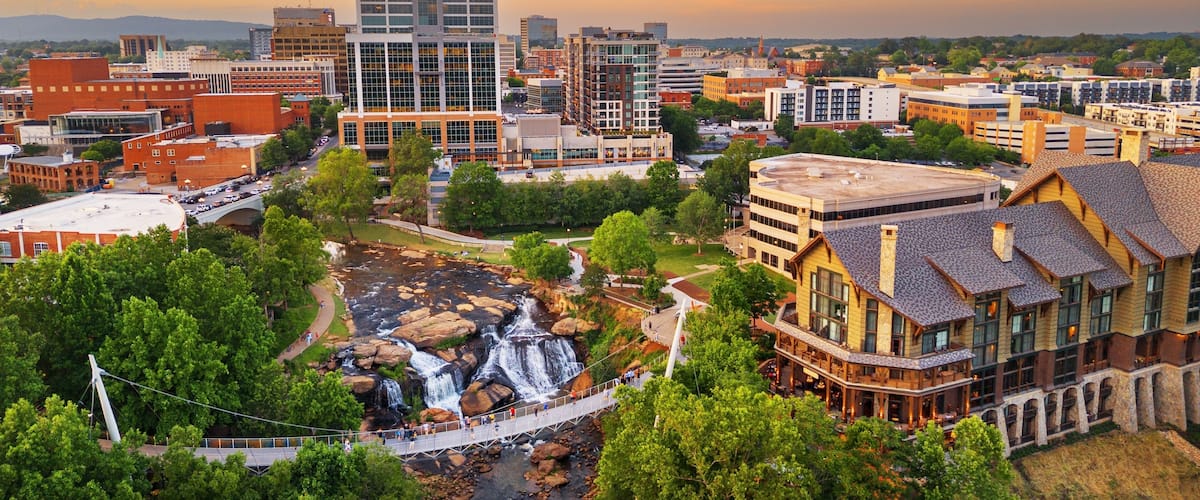 A cityscape with a prominent modern building, a waterfall, and surrounding greenery.