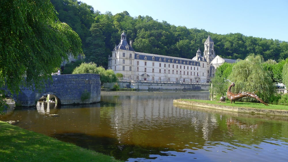 Un bâtiment historique doté d’une grande tour et orné d’une statue d’oiseau au bord de l’eau.