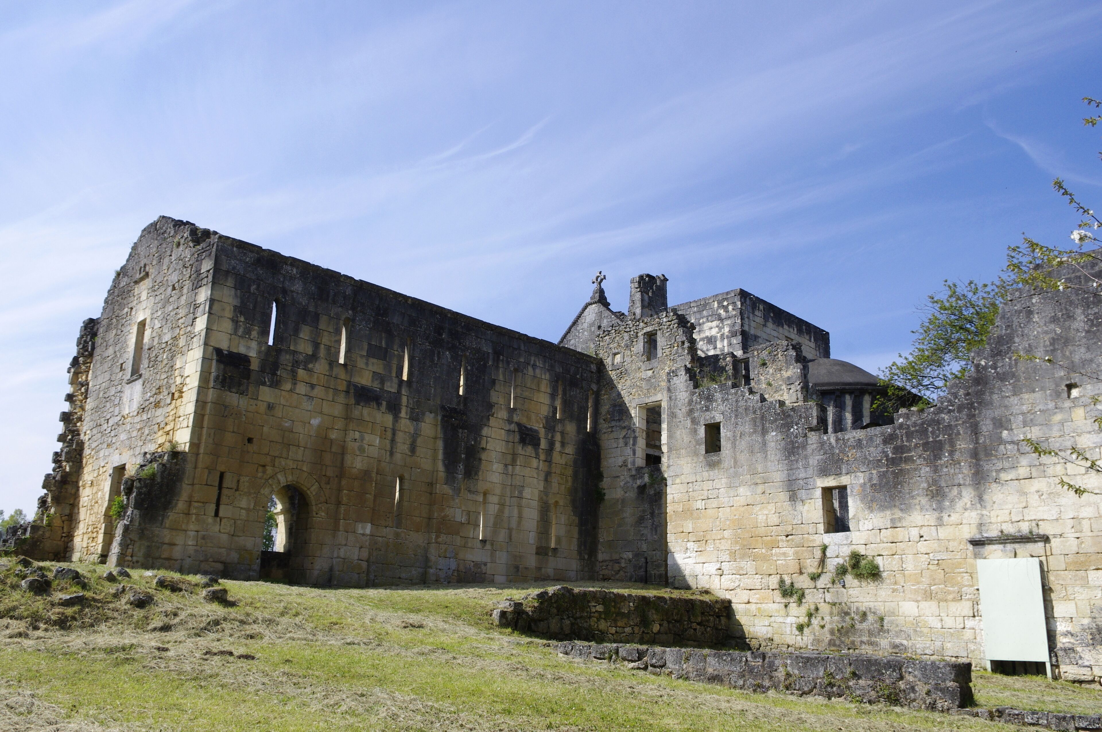 An ancient stone castle with ruins and overgrown grass.
