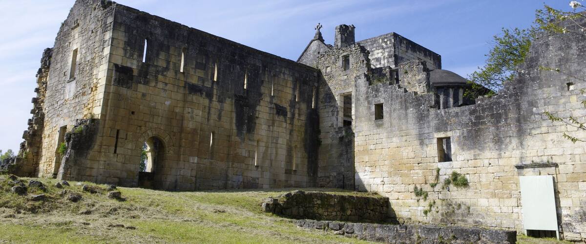 An ancient stone castle with ruins and overgrown grass.