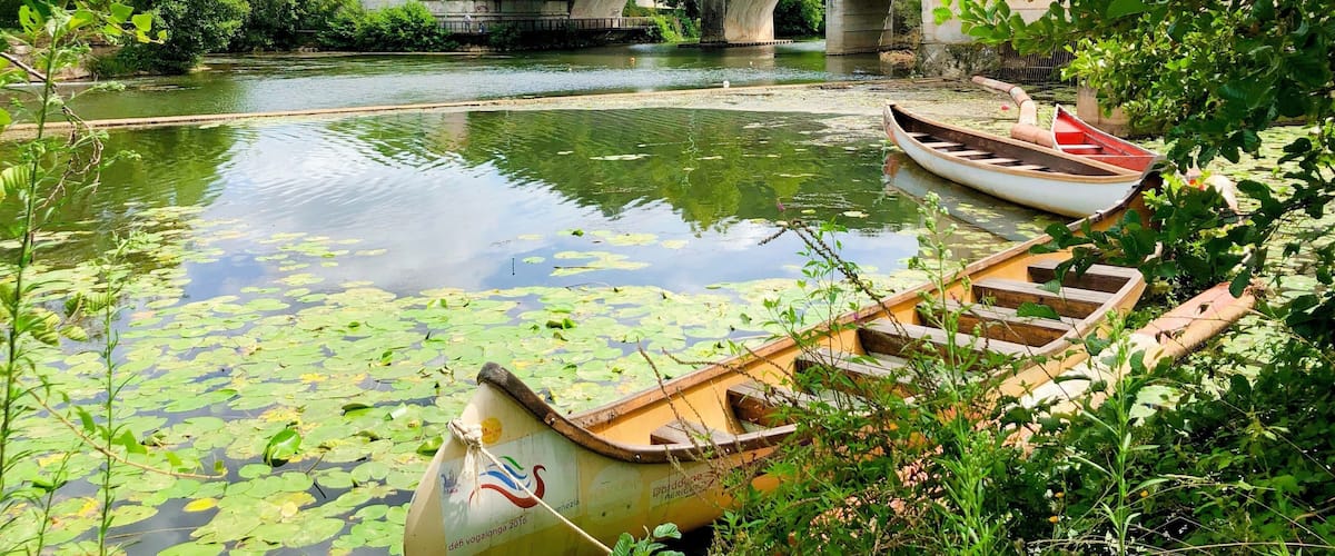 A river with boats, a bridge, and greenery.