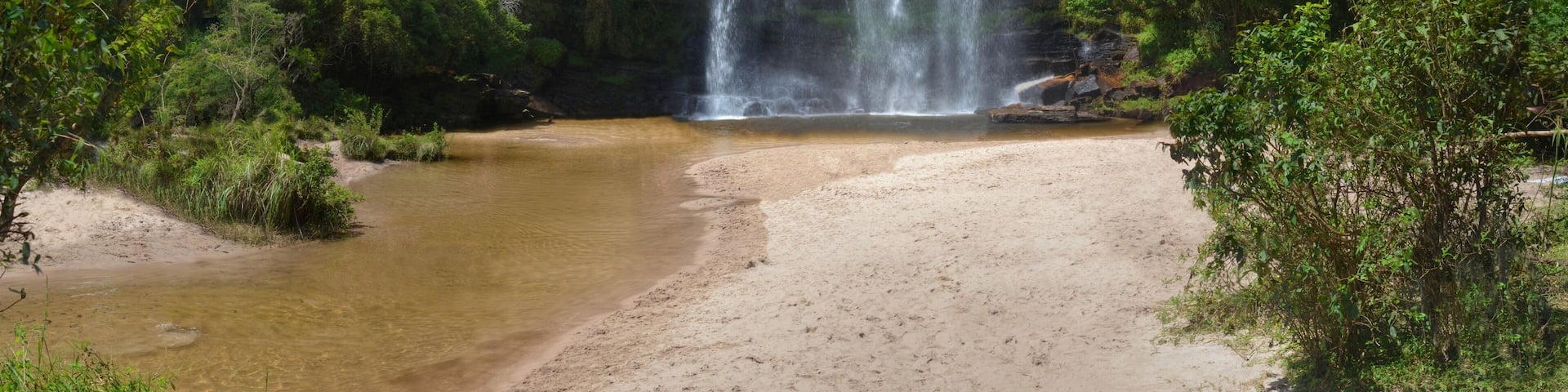 A waterfall cascading into a clear pool surrounded by dense forest.