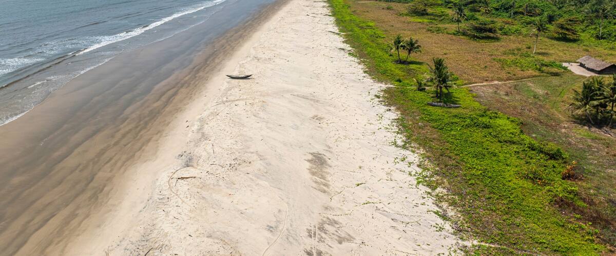 A beach with a boat, a sandy shore, and a forested area.