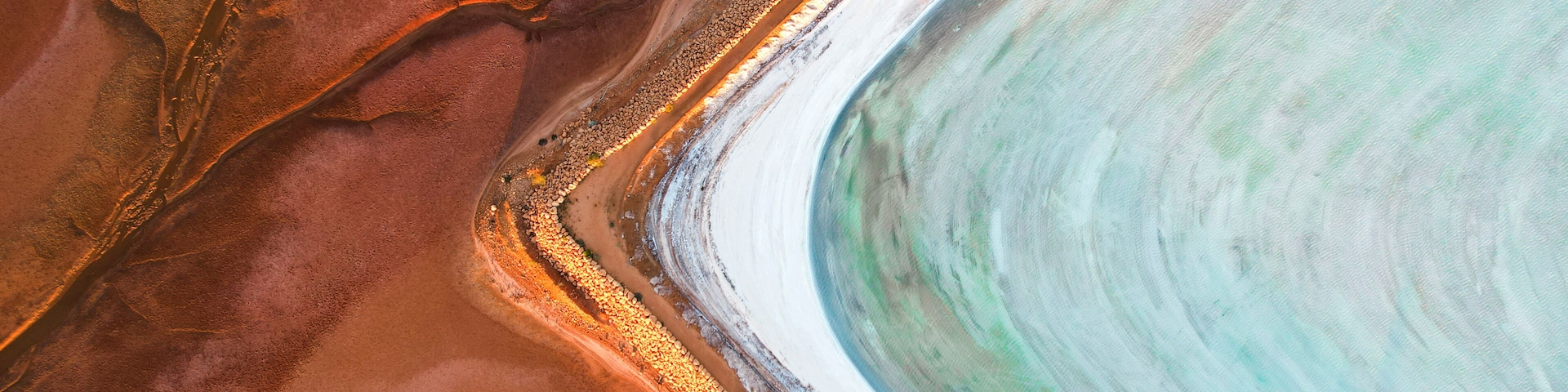 Vista aérea de un delta fluvial con canales de agua bien definidos y terreno circundante rojizo.