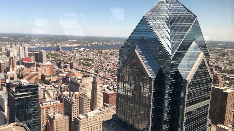 A cityscape with a prominent glass skyscraper featuring a unique triangular design.