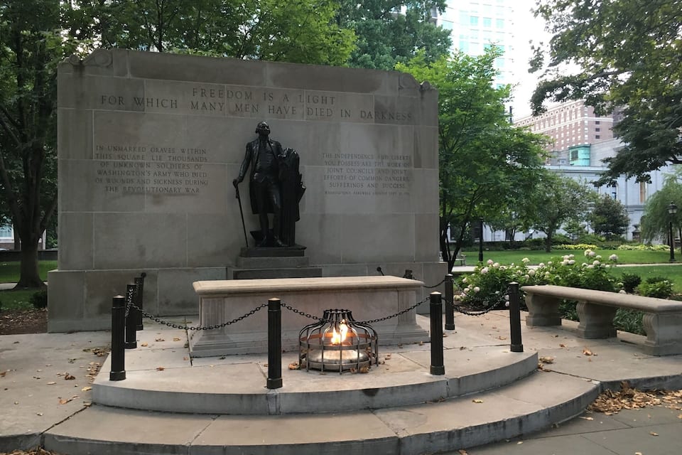 A memorial with a statue, engraved text, and a candle.