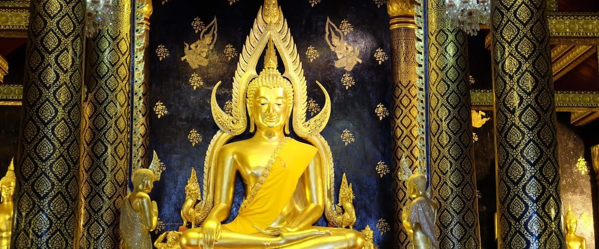 A golden Buddha statue in a temple with intricate patterns and decorations.