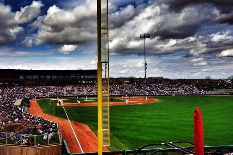 Estadi de beisbol amb una gran multitud, un pal de llum groc destacat i una bandera vermella.