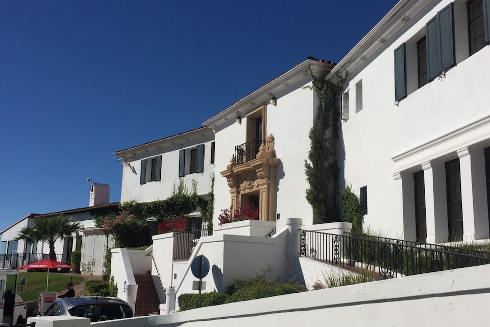 A white building with a balcony and a red umbrella.