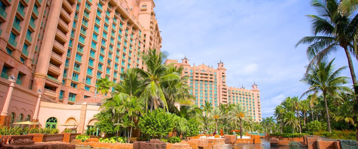 A resort with a large building, palm trees, and a water feature.