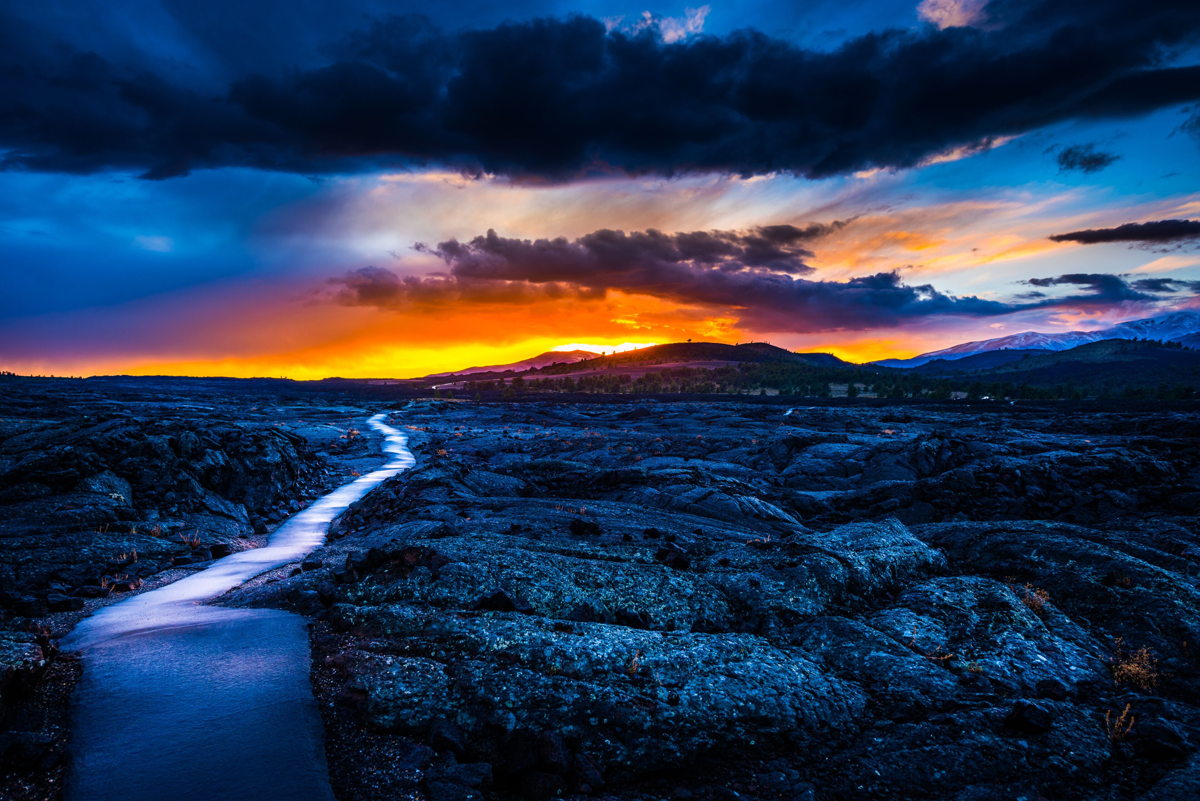 Campo de lava com um caminho que leva em direção a um pôr do sol.