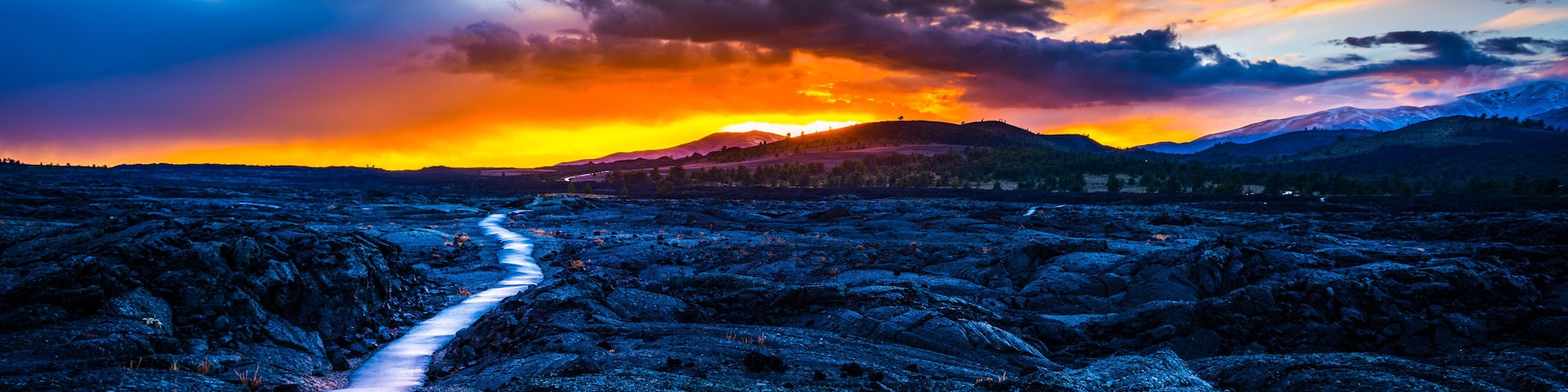 Campo de lava com um caminho que leva em direção a um pôr do sol.