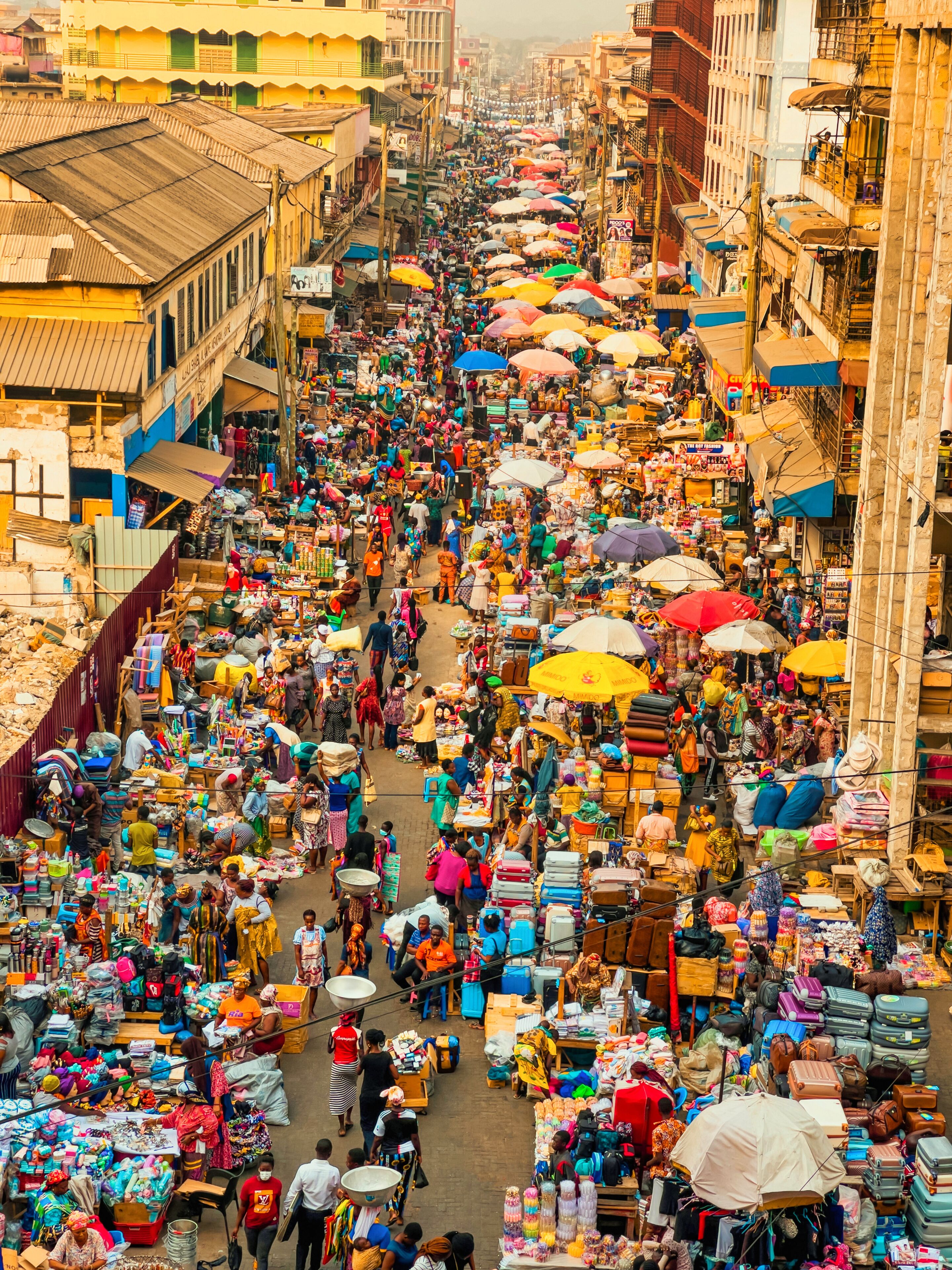 Accra, Ghana - 05 November 2022: Aerial view of Makola Market, a vibrant tapestry of humanity and commerce, where colorful umbrellas and tightly packed stalls burst with life beneath the African sun.