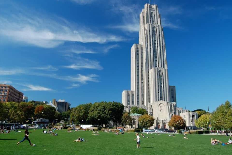 A large, tall building with vertical lines, surrounded by a park with people and trees.