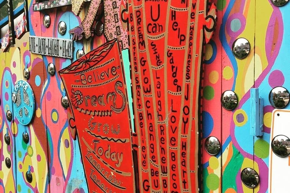 A colorful wall with various signs and decorations, including a prominent red sign with the word 'Believe' and other motivational phrases.
