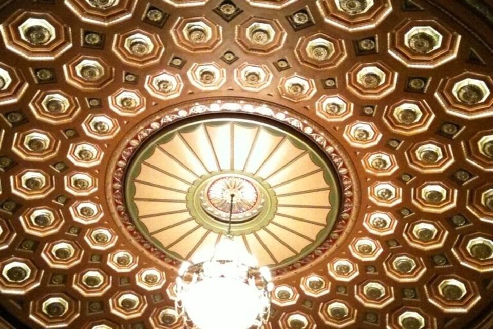 Een gedetailleerd plafond met een centraal, rond ontwerp, omringd door hexagonale patronen.