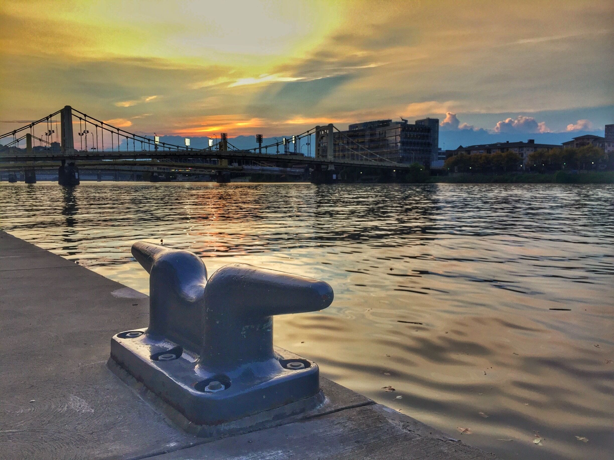 Un paisaje costero con un puente, agua tranquila y un atardecer.