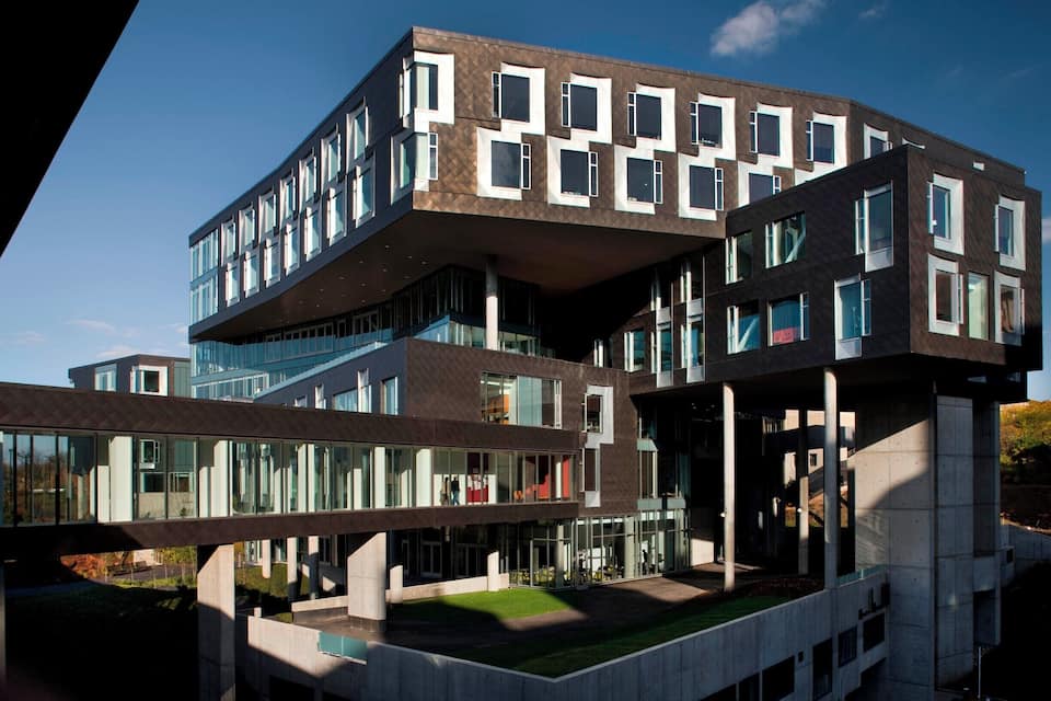 A modern multi-story building with a unique architectural design, featuring a mix of glass and concrete elements.