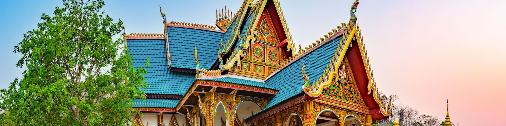 A traditional Thai temple with ornate architecture, a blue roof, and golden decorations.