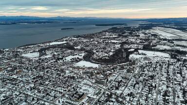 Plattsburgh, new york dusted in winter snow, aerial view of commercial and residential neighborhoods, winding saranac river, plattsburgh international airport, lake champlain horizon