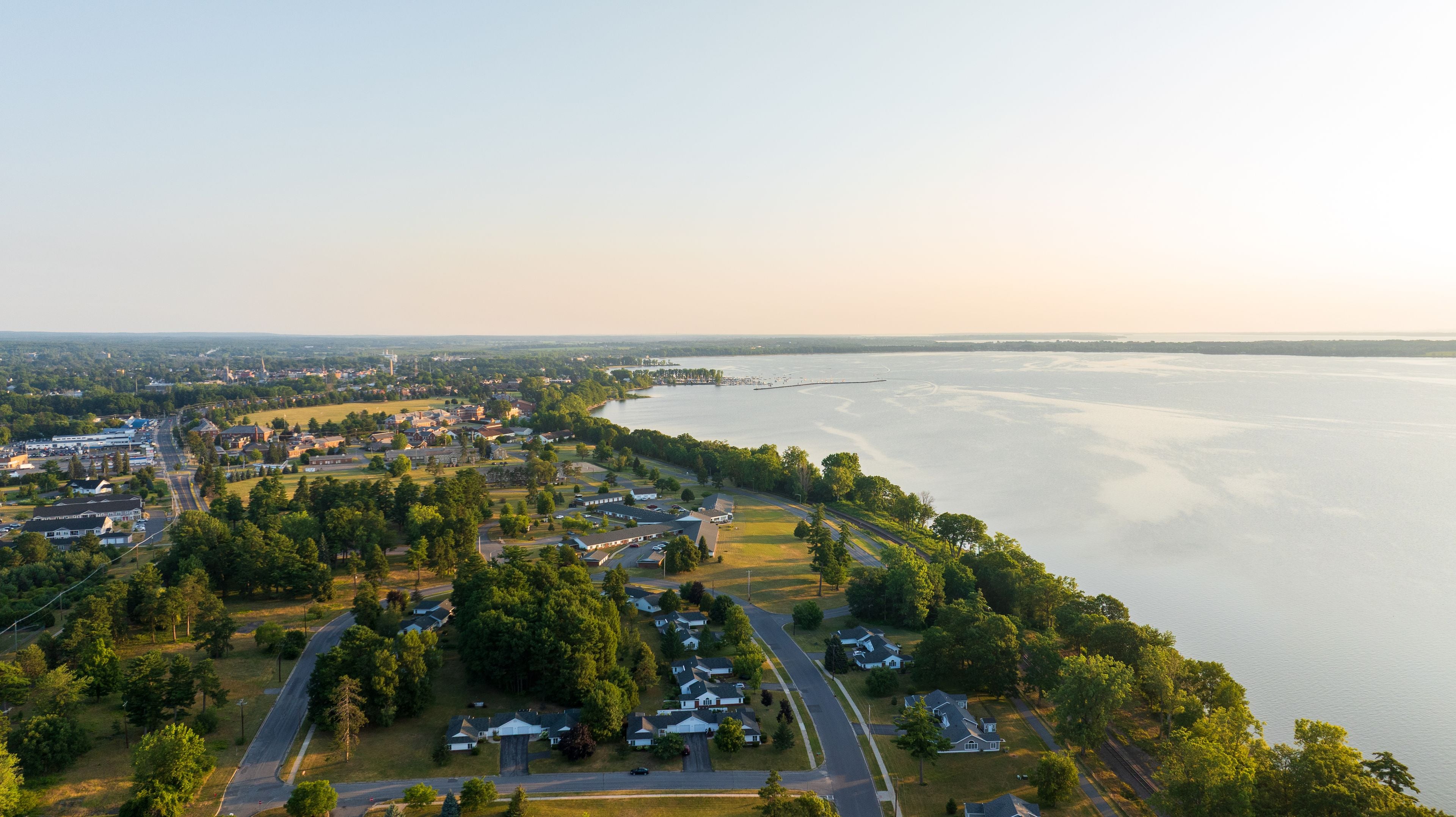 An aerial view of a lakeside community with residential areas, roads, and a distant shoreline.