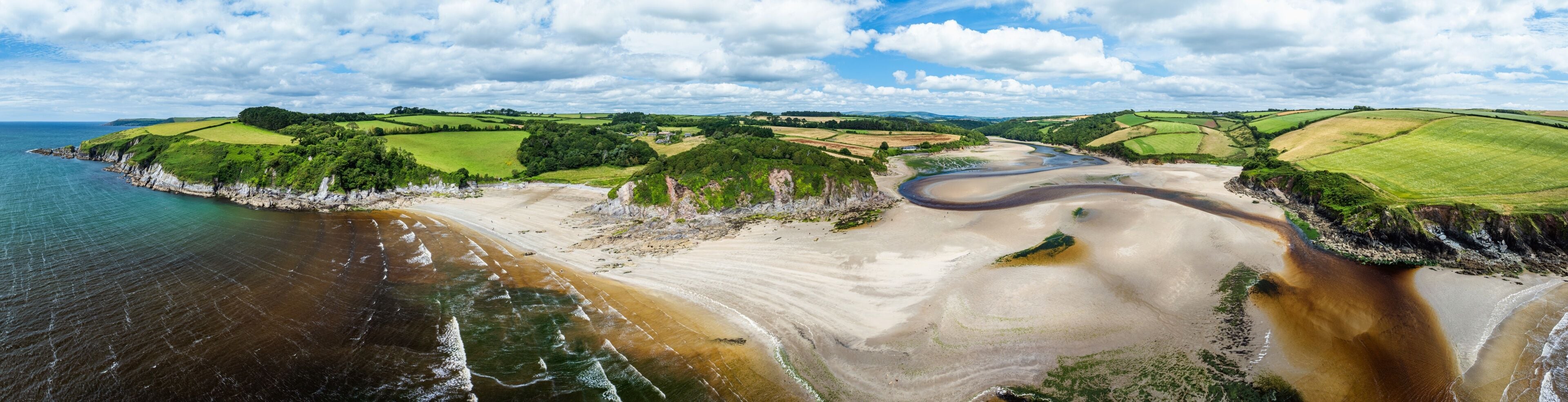 Un paisaje costero con un río sinuoso, campos verdes y acantilados.
