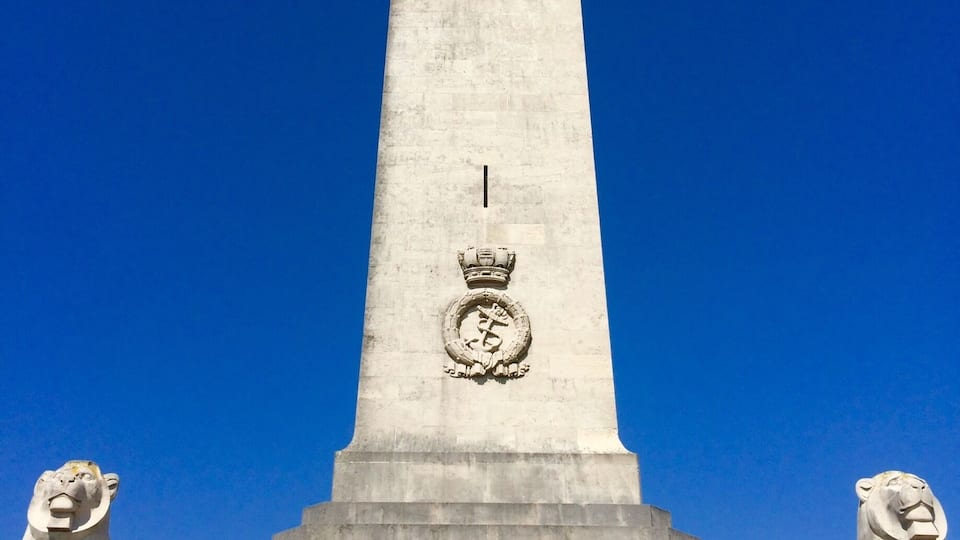 Een hoog monument met een standbeeld van een leeuw aan de voet en een kroon bovenop.
