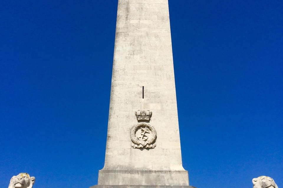 A tall monument with a lion statue at the base and a crown at the top.