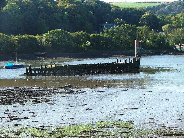 Hulk, Hooe Lake. Within the eastern end of Hooe Lake are the remnants of a number of old 'hulks' abandoned during the early part of the 20th century. Beyond and behind the first line of trees upon the shore is the local sewage works, with the sludge loading point immediately behind the bow of the hulk.