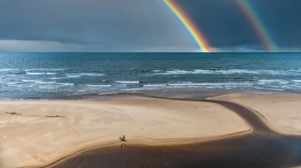 Colorful rainbow and rain over a sandy beach and estuary of small stream at the Baltic Beach, Europe