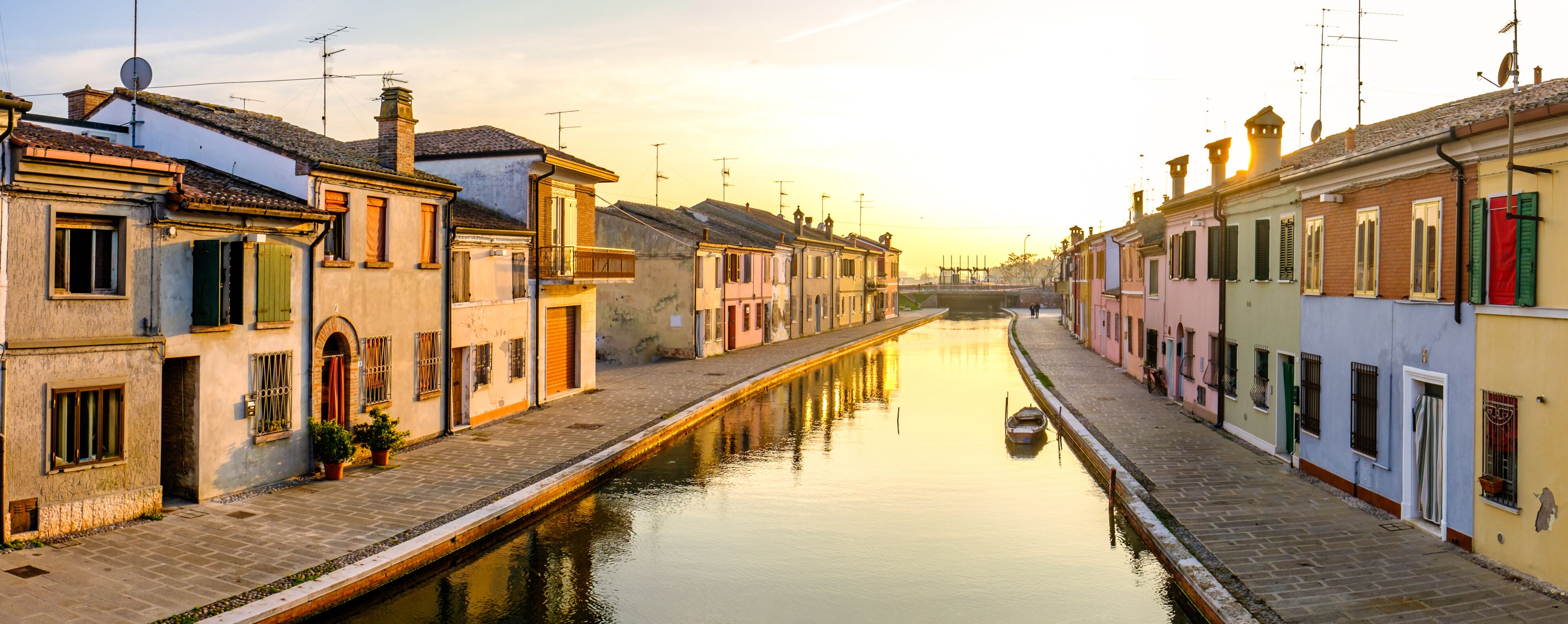 A canal flanked by historic buildings with a boat docked on the right.