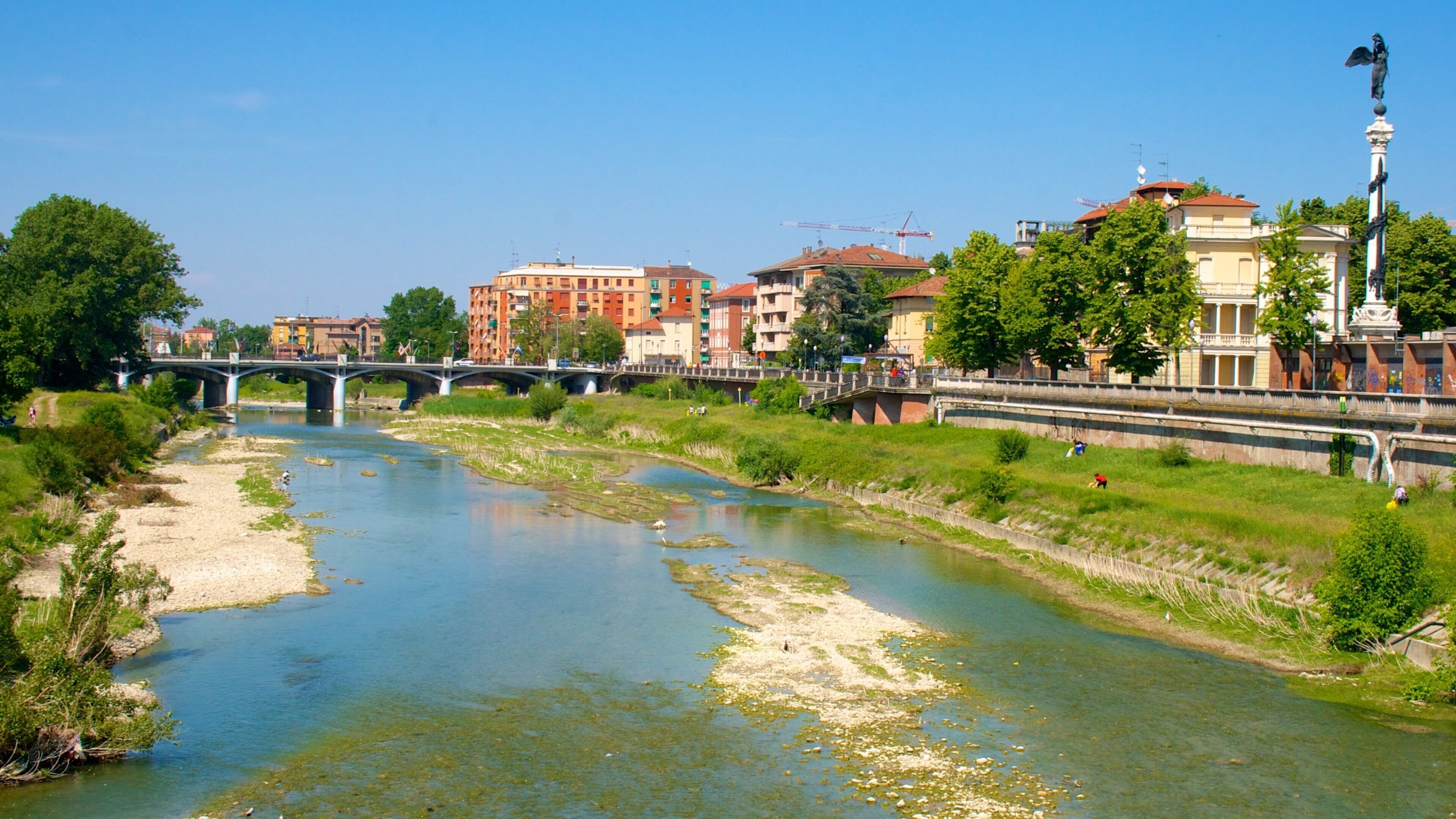 A river with a bridge, buildings, and a statue.