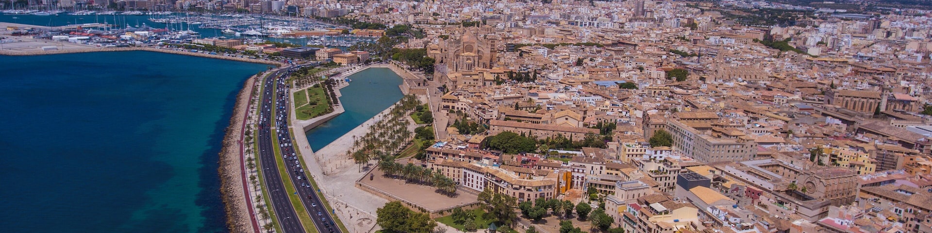 A coastal city with a marina, a long beachfront promenade, and dense urban buildings.