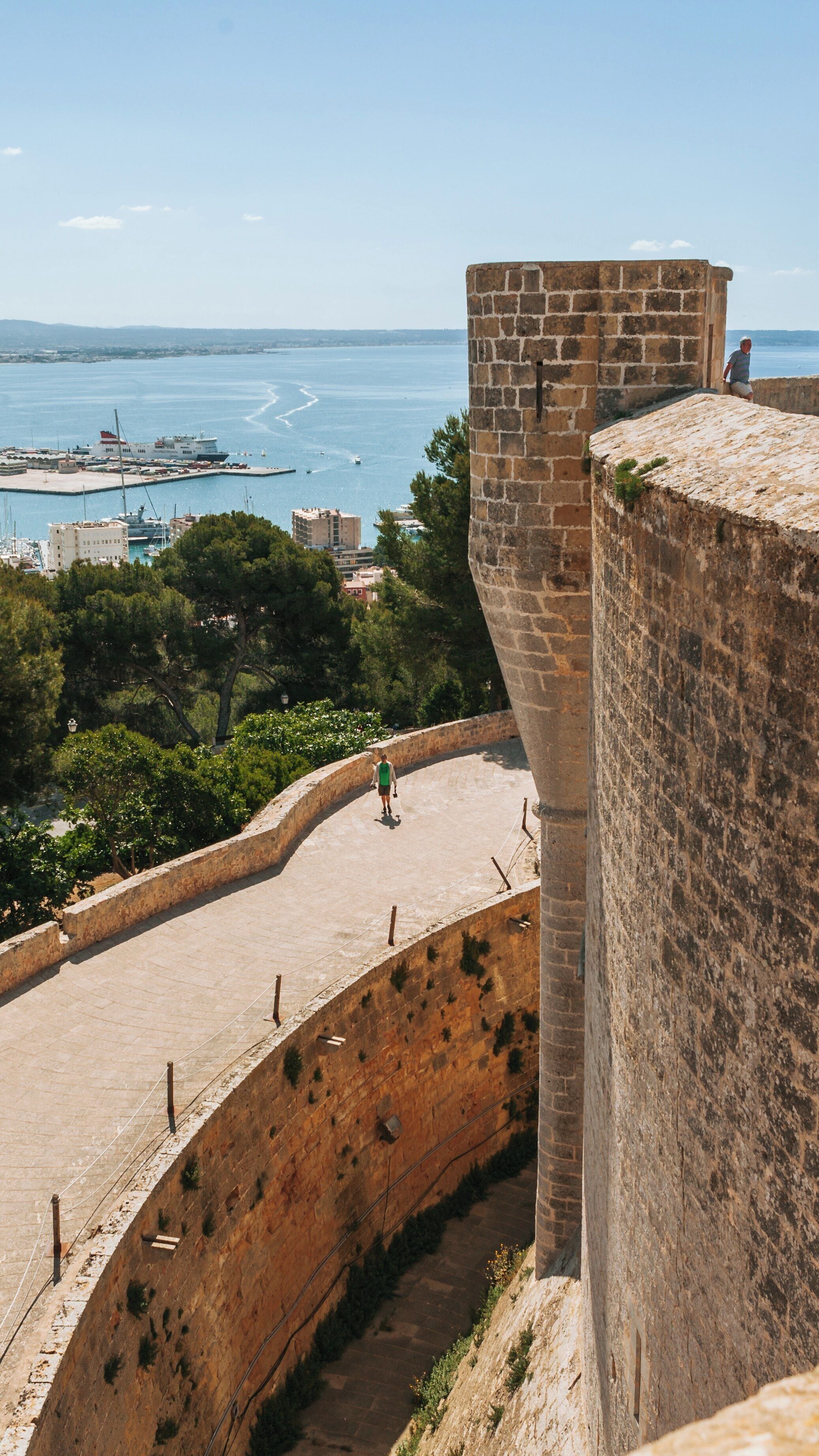 Bellver Castle offers a stunning view of Palma de Mallorca's coastline and harbor, showcasing its historical architecture and scenic beauty under clear skies