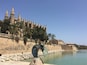Une cathédrale historique, dotée de flèches, bordée de palmiers et abritant une grande sculpture de Salvador Dalí.