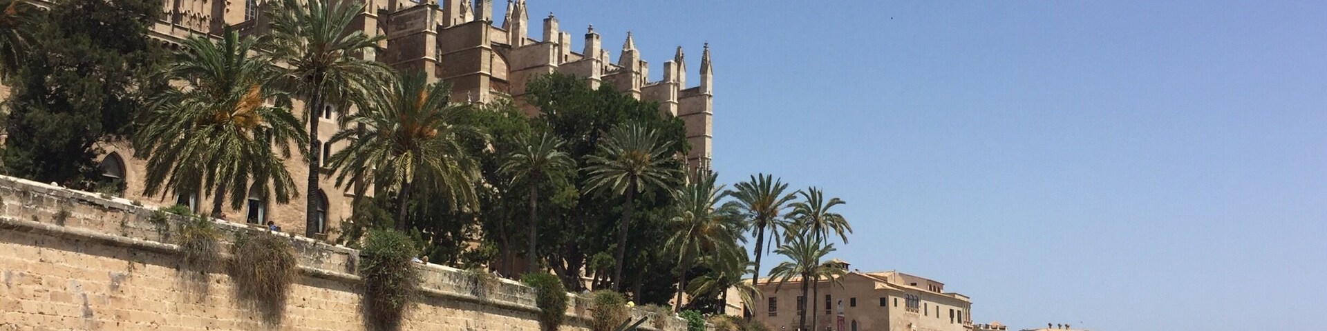 Una catedral histórica con agujas, palmeras y una gran escultura de Salvador Dalí.