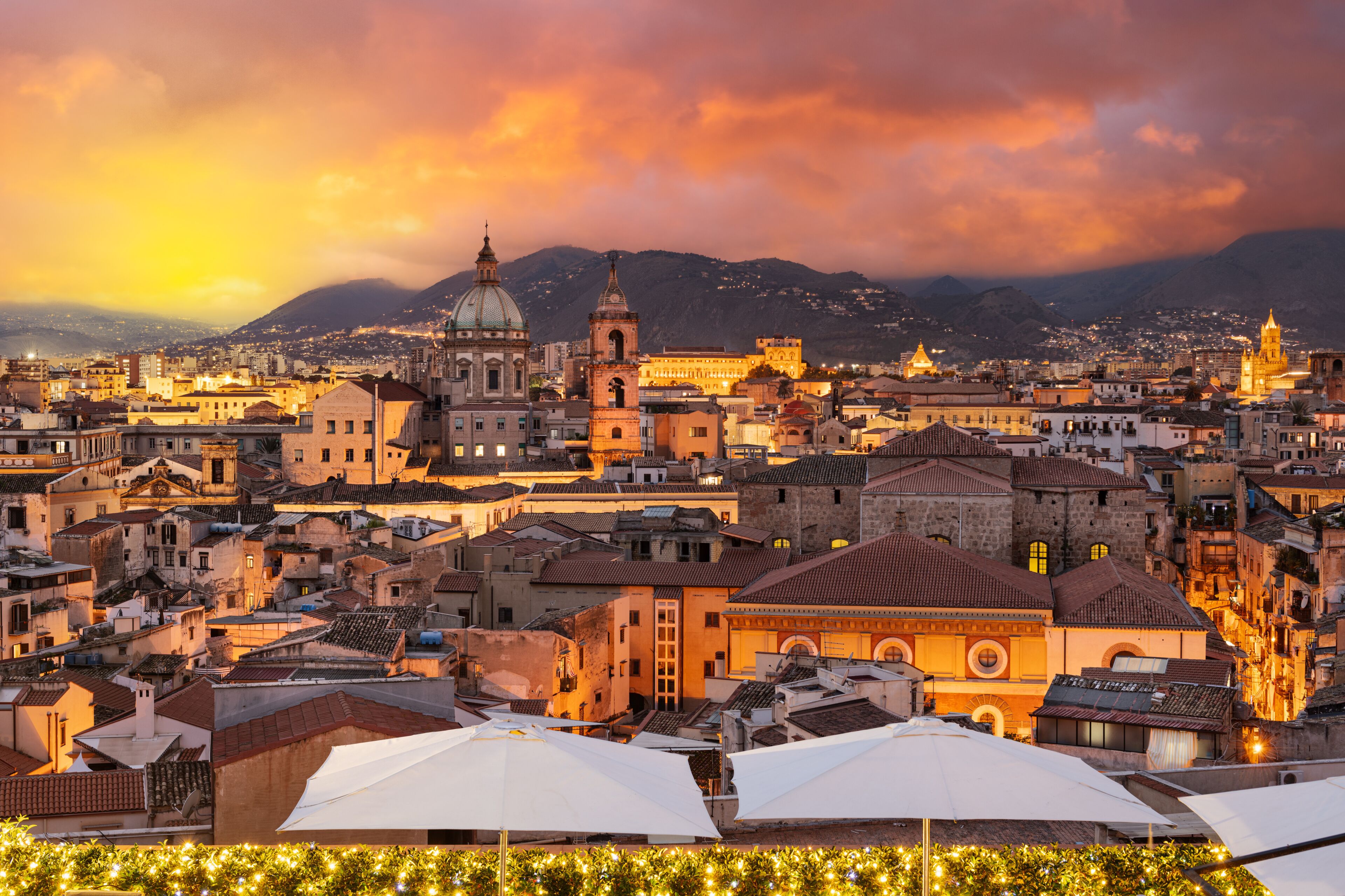 A cityscape with historic buildings, a prominent dome, and a mountain backdrop.