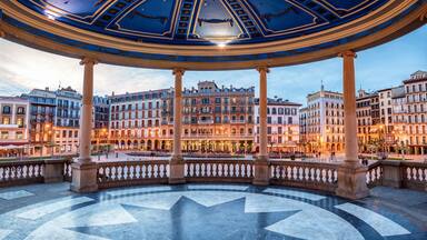 A grand plaza with a central circular fountain, surrounded by classical architecture and a domed ceiling.