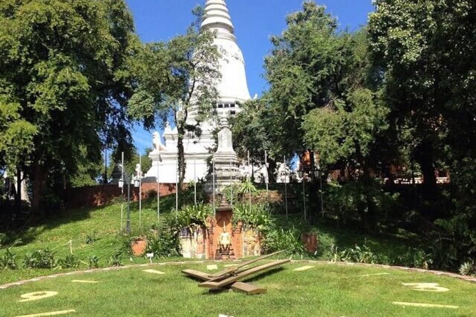 A white pagoda surrounded by a well-maintained garden with a clear sky.