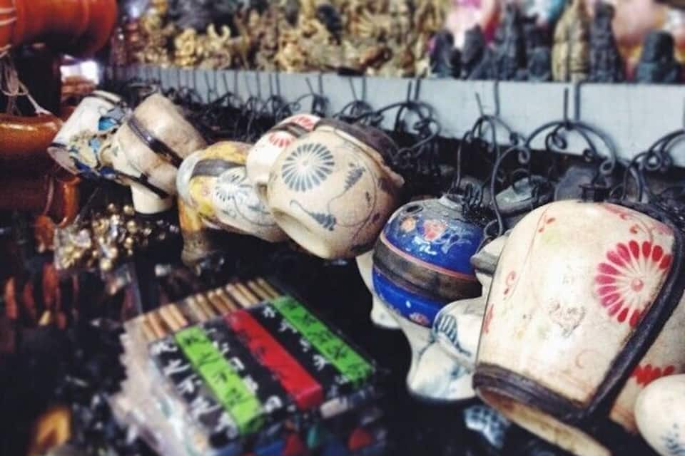 Variedad de artículos de cerámica, como jarrones y cuencos, exhibidos en ganchos.