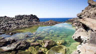 Un littoral rocheux, avec une eau limpide et une mer calme.