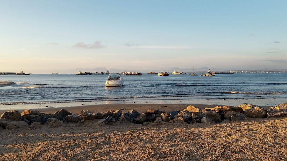 Ein Strand mit felsiger Küste und mehreren Booten im Wasser.
