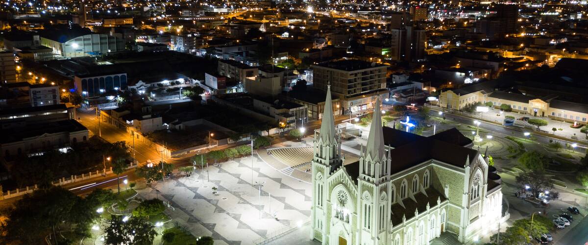 A cathedral with twin spires, surrounded by a plaza and a busy street at night.