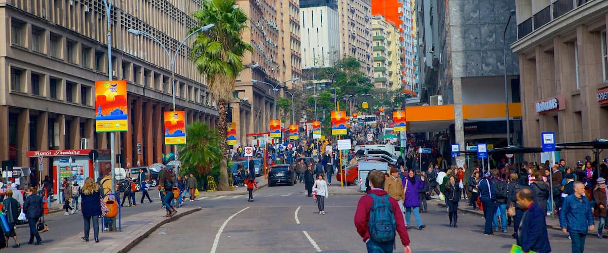 A busy urban street with tall buildings, palm trees, and pedestrians.